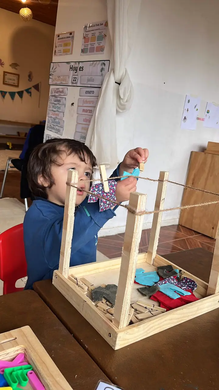 Niño colgando telas en un tendedero de madera